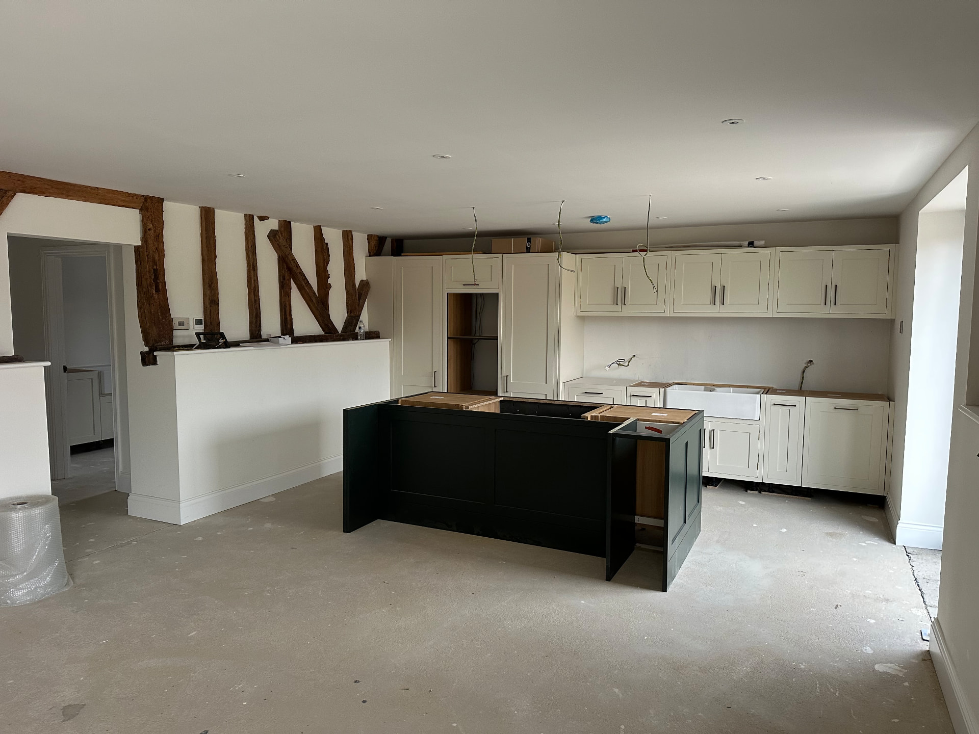 Two-tone kitchen installation in progress beside original timber beams