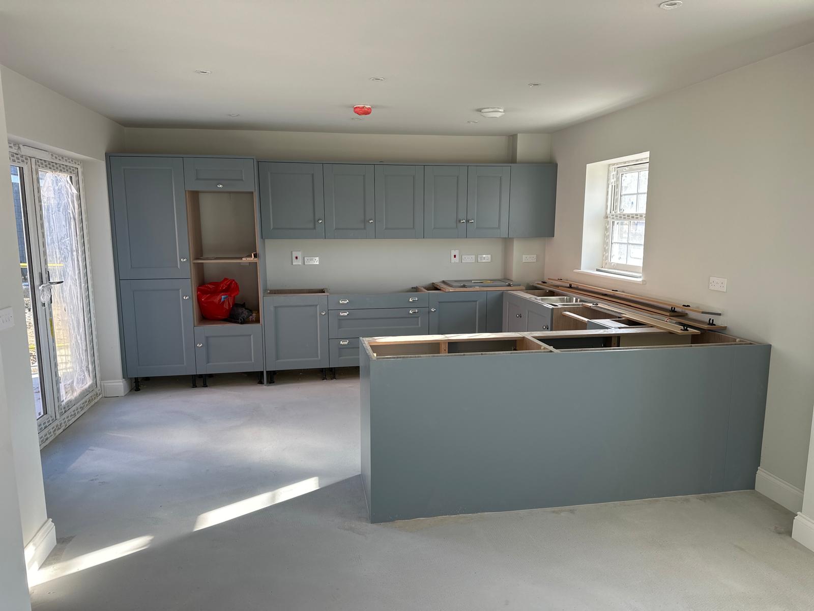 Blue-grey kitchen cabinets during installation
