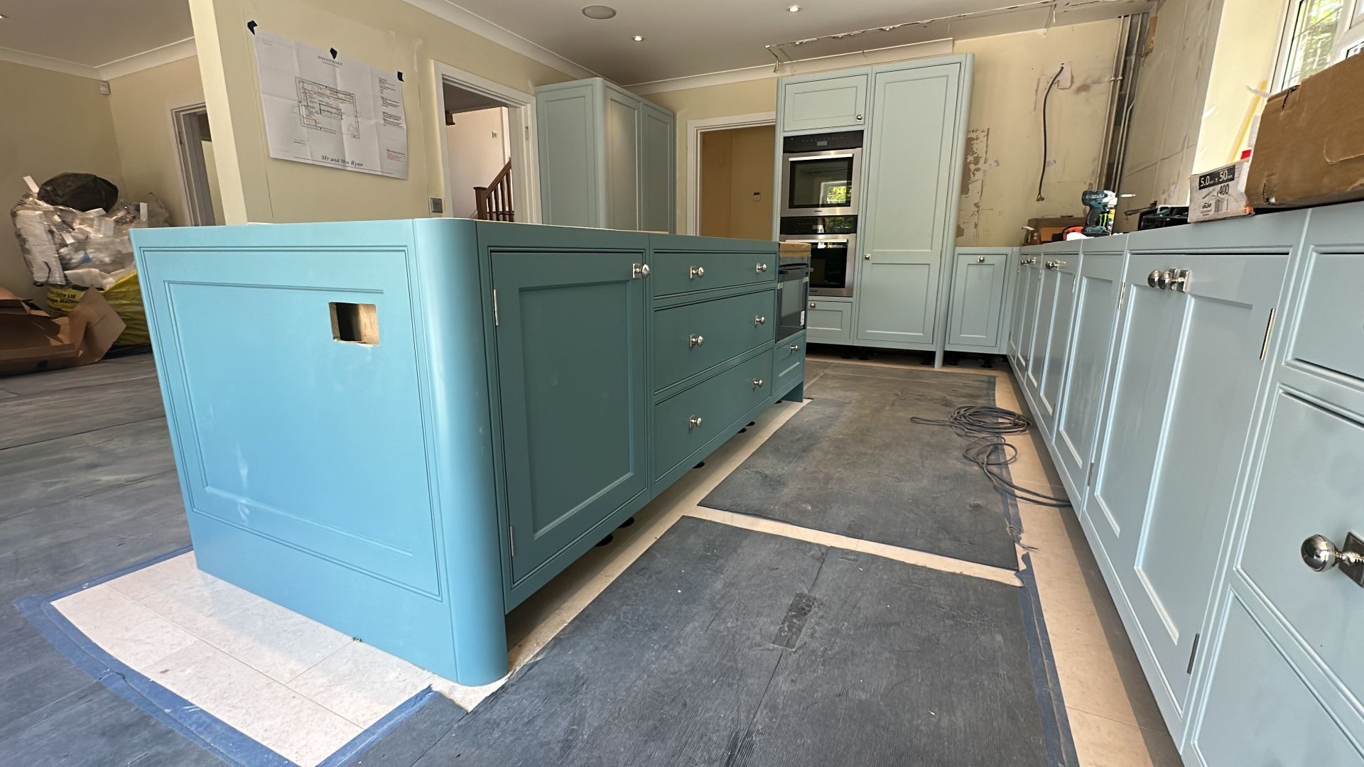 The curved painted island and tall cabinetry being fitted