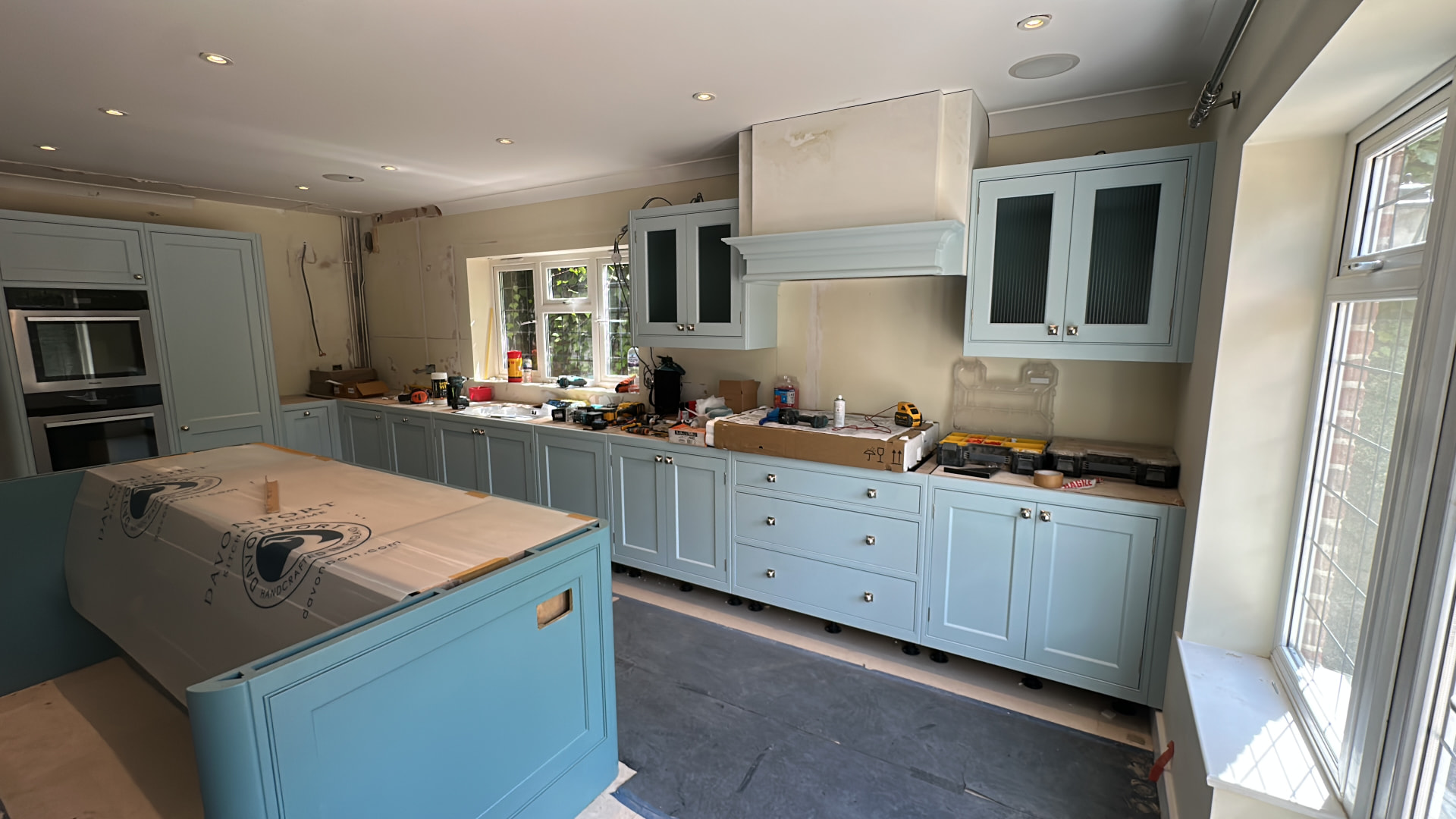 Duck-egg blue hand painted cabinets mid-fitting, island still protected